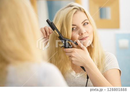 Woman using hair curler 128801888