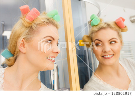 Blonde woman using hair rollers 128801917