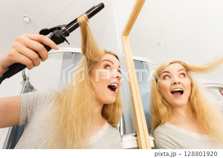 Woman using hair curler Woman using hair curler 128801920