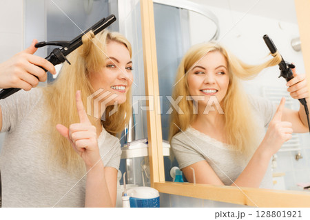Woman using hair curler Woman using hair curler 128801921