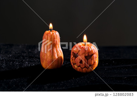 Halloween-style candles on a dark background. Festive decor. 128802083