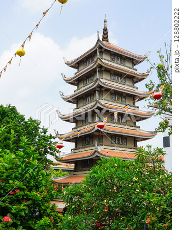 Vinh Nghiem Pagoda Tower in Saigon Surrounded by Lanterns, Flags, and Blooming Garden Vinh Nghiem Pagoda Tower in Saigon Surrounded by Lanterns, Flags, and Blooming Garden 128802222