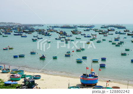 Colorful Basket and Fishing Boats Dot the Tranquil Bay of Mui Ne Under a Calm Sky in Vietnam Colorful Basket and Fishing Boats Dot the Tranquil Bay of Mui Ne Under a Calm Sky in Vietnam 128802242