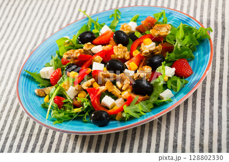 Arugula salad with vegetables, soft cheese, strawberry 128802330