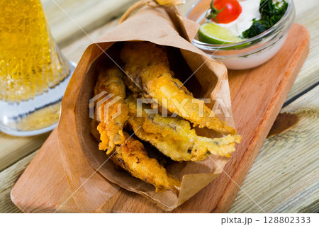 Fried in batter anchovies with creamy cheese sauce and greens Fried in batter anchovies with creamy cheese sauce and greens 128802333
