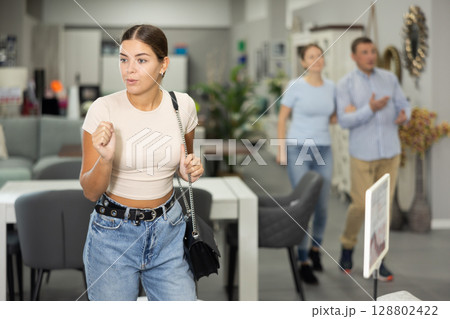 Interested young girl examining pieces of furniture in store 128802422