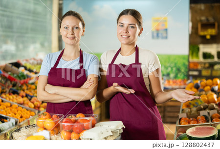 Happy two female sellers wearing apron and standing next to organic foods in supermarket 128802437
