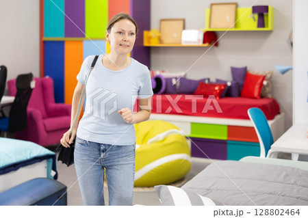 Interested woman choosing functional furniture for home in shop Interested woman choosing functional furniture for home in shop 128802464