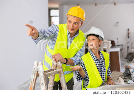 Young boy and his father discussing work plan in new apartment Young boy and his father discussing work plan in new apartment 128802488