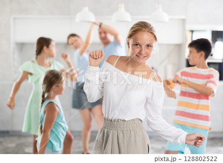Behind cheerful girl, big family of parents, sisters, brother is rejoicing, dancing, having fun. Behind cheerful girl, big family of parents, sisters, brother is rejoicing, dancing, having fun. 128802522