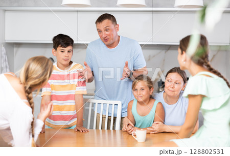 Friendly family gathered at table and cheerfully discuss past day. 128802531