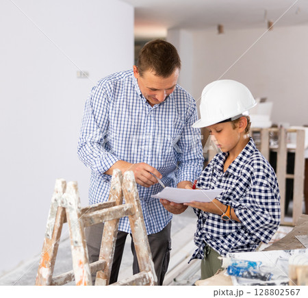 Man showing son blueprints in new home 128802567