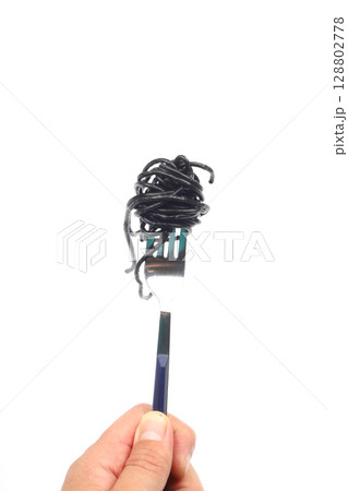 Spaghetti pasta with black ink squid on a fork on an isolated white background. Spaghetti pasta with black ink squid on a fork on an isolated white background. 128802778