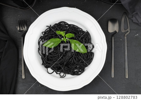 Spaghetti pasta with black ink squids on wooden background. Spaghetti pasta with black ink squids on wooden background. 128802783
