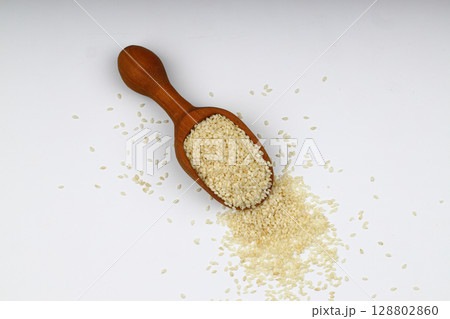 Sesame seeds in wooden scoop, isolated on white background. Organic dry sesame seeds. 128802860