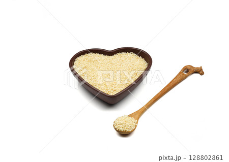 White sesame seeds in a wooden bowl. Top view. A copy of the space. heart-shaped bowl 128802861