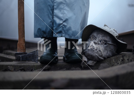 Creepy person with axe and severed head of scarecrow 128803035