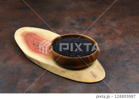 Black cumin seeds and essential oil with bowl and wooden shovel or spoon. Nigella Sativa in glass bottle. Organic herbal medicine for many diseases 128803087