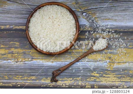 Raw white rice on black background. Long uncooked rice in wooden plate. Natural organic food. Traditional Asian cereal culture. Raw white rice on black background. Long uncooked rice in wooden plate. Natural organic food. Traditional Asian cereal culture. 128803124