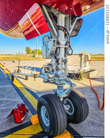 Close-up view of aircraft nose landing gear and maintenance details on runway. High quality photo Close-up view of aircraft nose landing gear and maintenance details on runway. High quality photo 128803133