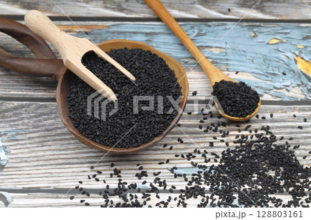 Black cumin seeds and essential oil with bowl and wooden shovel or spoon. Nigella Sativa in glass bottle. Organic herbal medicine for many diseases Black cumin seeds and essential oil with bowl and wooden shovel or spoon. Nigella Sativa in glass bottle. Organic herbal medicine for many diseases 128803161