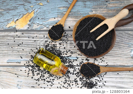 Black cumin seeds and essential oil with bowl and wooden shovel or spoon. Nigella Sativa in glass bottle. Organic herbal medicine for many diseases Black cumin seeds and essential oil with bowl and wooden shovel or spoon. Nigella Sativa in glass bottle. Organic herbal medicine for many diseases 128803164