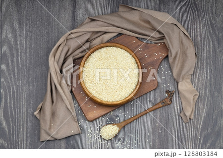 Top view closeup of freshly harvested white sesame in wooden bowl isolated on wooden background with clipping path. 128803184