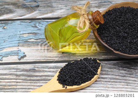 Black cumin seeds and essential oil with bowl and wooden shovel or spoon. Nigella Sativa in glass bottle. Organic herbal medicine for many diseases Black cumin seeds and essential oil with bowl and wooden shovel or spoon. Nigella Sativa in glass bottle. Organic herbal medicine for many diseases 128803201