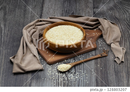 Top view closeup of freshly harvested white sesame in wooden bowl isolated on wooden background with clipping path. 128803207
