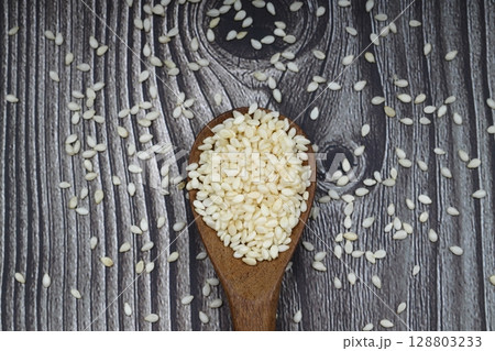 close up of sesame flour and sesame seeds in a wooden spoon. alternative type of flour. gluten free product. flour for dieting and low carb healthy meal 128803233