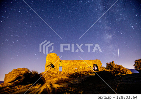 A view of the stars of the Milky Way with a mountain top in the foreground. Night sky nature summer landscape. Perseid Meteor Shower observation 128803364