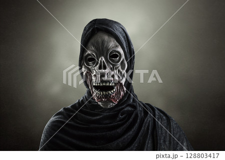 Portrait of a zombie with hooded cape over dark misty background 128803417