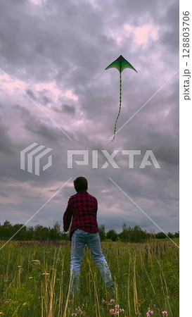 child playing kite sky background, children play outdoor nature, Dramatic Sky and Playful Spirit, Kite Flight in a Wild Meadow, Red Plaid Shirt Adventure, The Wonder of Flight, Freedom on the Open 128803706
