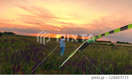 child boy running kite sunset, kid childhood dream happy family,silhouette outdoor play, Running through wildflower meadow, Sun setting on the horizon, Kid holding kite string, Vibrant sunset colors 128803715