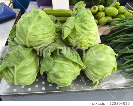 Fresh green cabbages stacked together at a vibrant outdoor market in spring 128804030