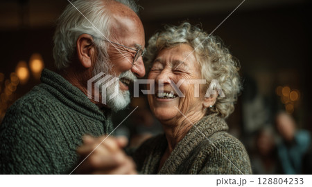 Elderly couple joyfully dancing together in their cozy living room Elderly couple joyfully dancing together in their cozy living room 128804233