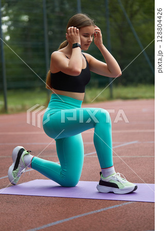 Fit woman exercising outdoors on a yoga mat, wearing stylish activewear, showcasing strength and determination in a vibrant setting. Workout concept Fit woman exercising outdoors on a yoga mat, wearing stylish activewear, showcasing strength and determination in a vibrant setting. Workout concept 128804426