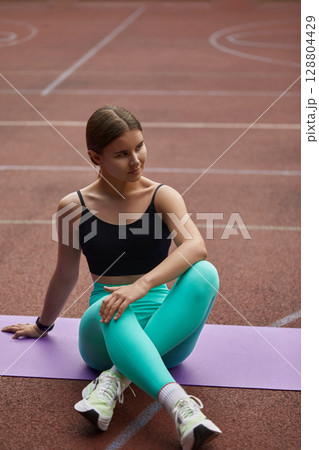 Fit woman exercising outdoors on a yoga mat, showcasing strength and flexibility in a vibrant athletic outfit, with a focus on health and wellness. Workout concept Fit woman exercising outdoors on a yoga mat, showcasing strength and flexibility in a vibrant athletic outfit, with a focus on health and wellness. Workout concept 128804429