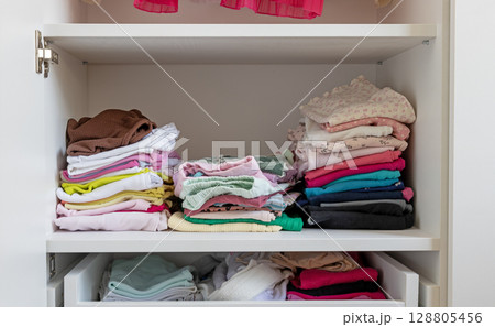Folded children's clothes in the closet, storage of children's clothes. 128805456