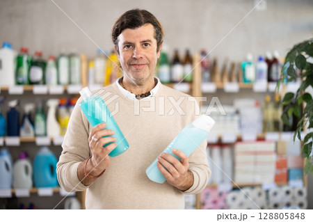 man chooses shampoo and shower gel in the store 128805848