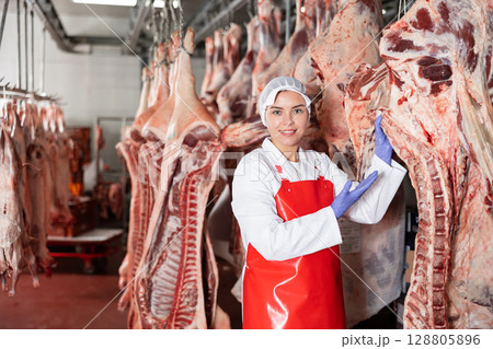 Female butcher showing beef chunk in meat storage Female butcher showing beef chunk in meat storage 128805896