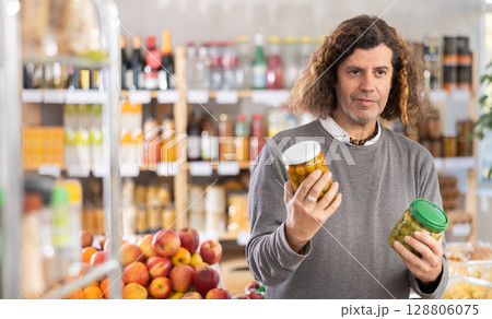 Adult man choosing olives in grocery store Adult man choosing olives in grocery store 128806075