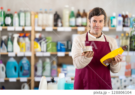 Man seller stands in trading hall of household store, offer goods Man seller stands in trading hall of household store, offer goods 128806104