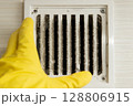 Cleaning technician wearing gloves checking dirty ventilation grille 128806915
