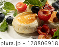 Cheesecakes with blueberries and cherries garnished with mint leaves on white plate 128806918