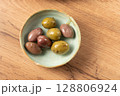 Green and brown olives seasoned with herbs in a ceramic bowl 128806924