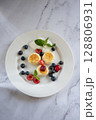 Cheesecakes with poppy seeds, blueberries, cherries and sour cream on white plate on marble table 128806931