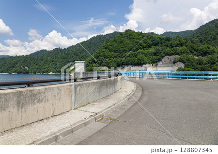 矢木沢ダム　アーチ式堤体の上を通る 128807345