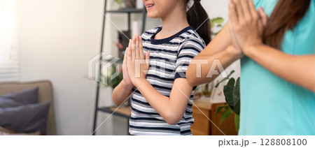 Mother and daughter practicing mindfulness with hands together 128808100