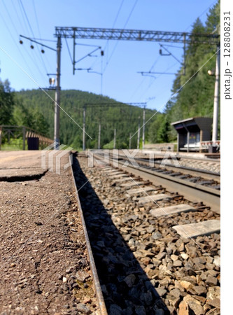 railway tracks leading to remote station surrounded by wilderness under clear blue sky. closeup. 128808231